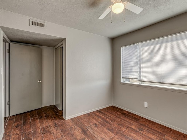 spare room with a textured ceiling, dark hardwood / wood-style flooring, and ceiling fan