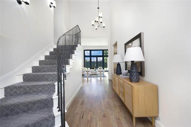 foyer entrance with a chandelier, french doors, a towering ceiling, and wood-type flooring