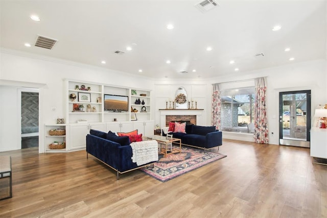 living room with crown molding and light wood-type flooring