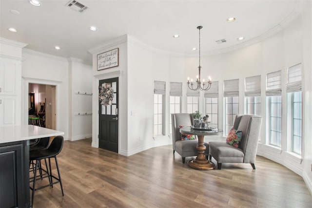 dining space featuring hardwood / wood-style flooring, ornamental molding, an inviting chandelier, and a wealth of natural light