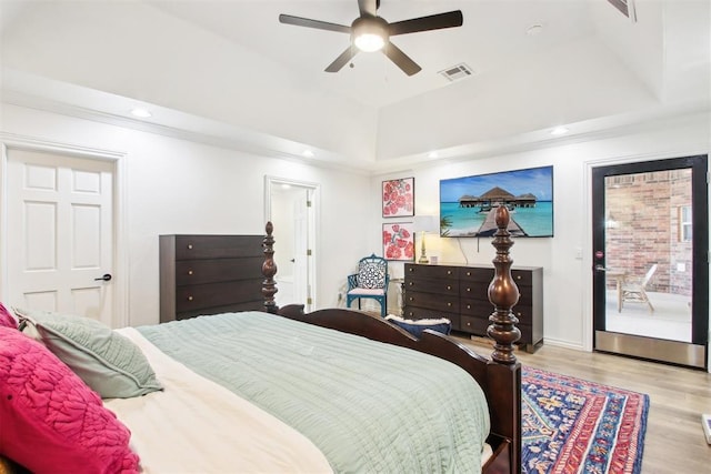 bedroom with light hardwood / wood-style flooring, access to exterior, ceiling fan, and a tray ceiling