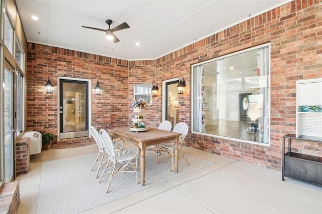 interior space with ceiling fan and brick wall