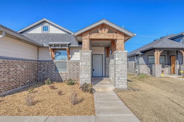 doorway to property with brick siding and roof with shingles