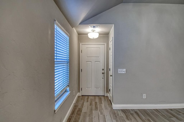 foyer entrance featuring light wood-type flooring and vaulted ceiling