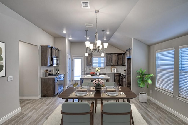 dining area featuring light wood-type flooring, lofted ceiling, and a notable chandelier