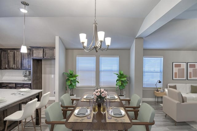 dining space featuring light hardwood / wood-style flooring, lofted ceiling, and a notable chandelier