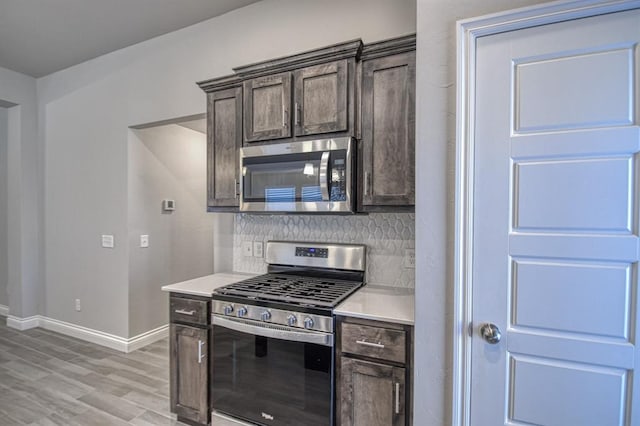 kitchen featuring decorative backsplash, appliances with stainless steel finishes, dark brown cabinetry, and light hardwood / wood-style floors