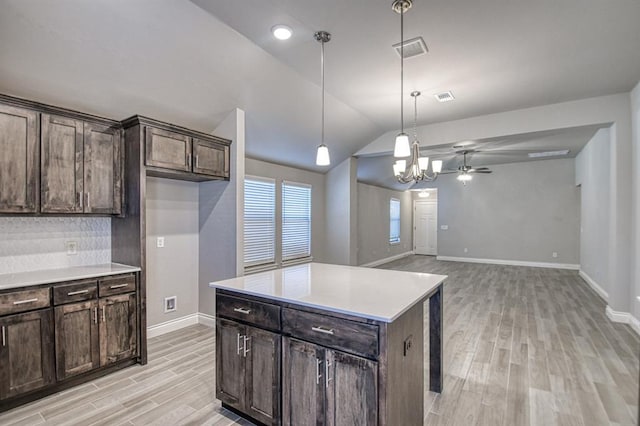 kitchen featuring backsplash, ceiling fan with notable chandelier, vaulted ceiling, pendant lighting, and a center island