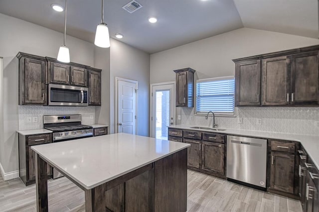 kitchen with decorative backsplash, appliances with stainless steel finishes, sink, a kitchen island, and lofted ceiling