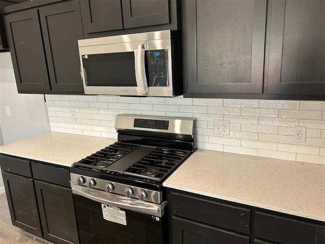 kitchen with decorative backsplash, stainless steel appliances, and light stone countertops