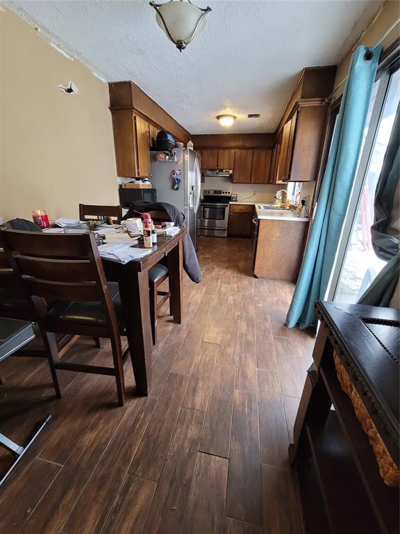 kitchen with appliances with stainless steel finishes, dark hardwood / wood-style flooring, sink, and a textured ceiling