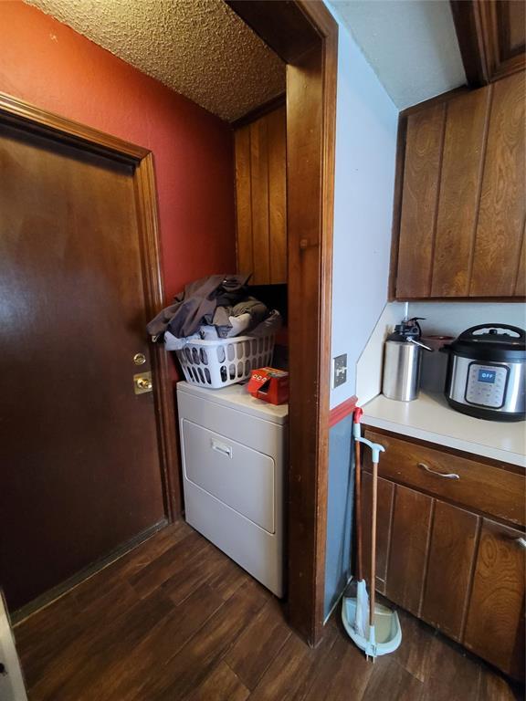 laundry area featuring washer / clothes dryer, a textured ceiling, cabinets, and dark wood-type flooring