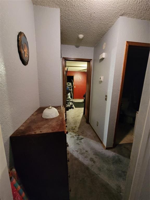 corridor with a textured ceiling and carpet flooring