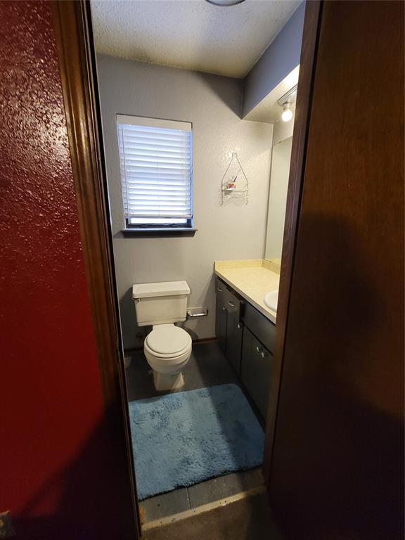 bathroom featuring a textured ceiling, vanity, and toilet