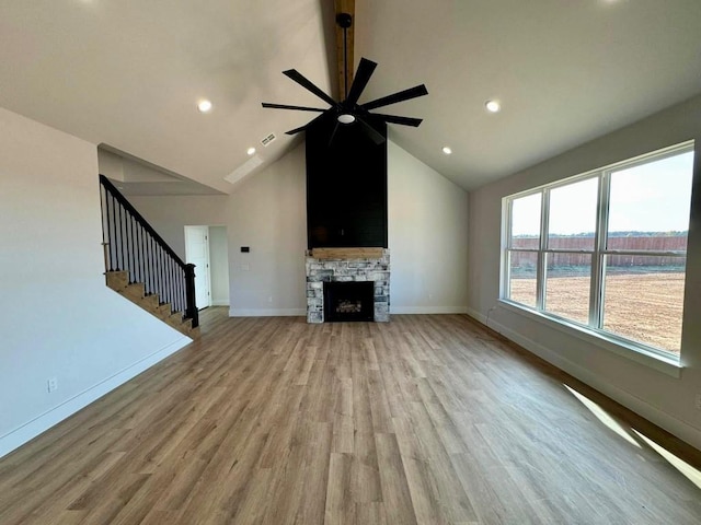 unfurnished living room with a stone fireplace, stairway, light wood-type flooring, and baseboards