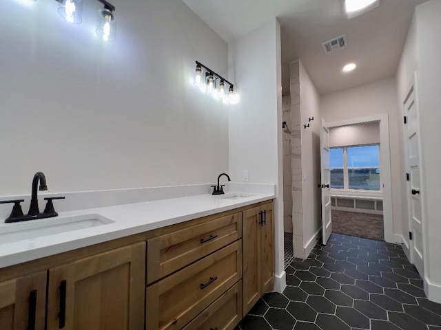 bathroom with visible vents, double sink, and tile patterned floors