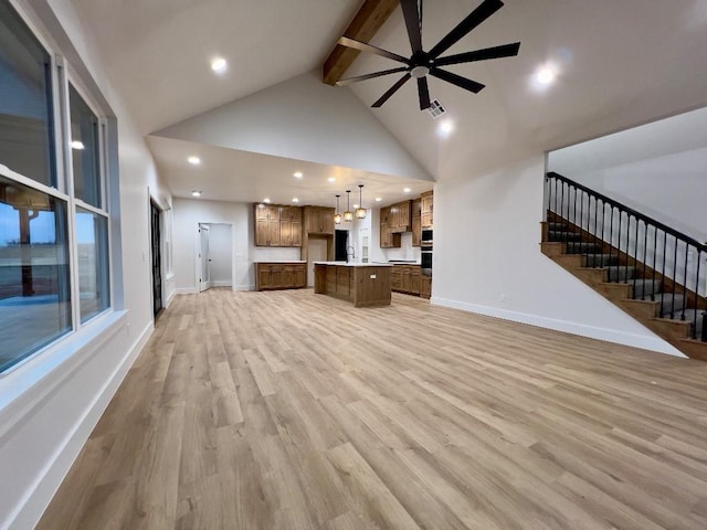 unfurnished living room with light wood finished floors, baseboards, visible vents, stairs, and high vaulted ceiling