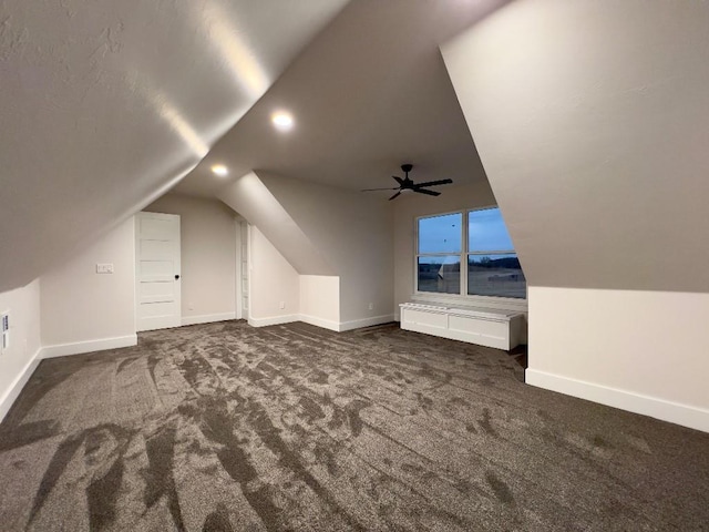 additional living space featuring dark colored carpet, lofted ceiling, and baseboards