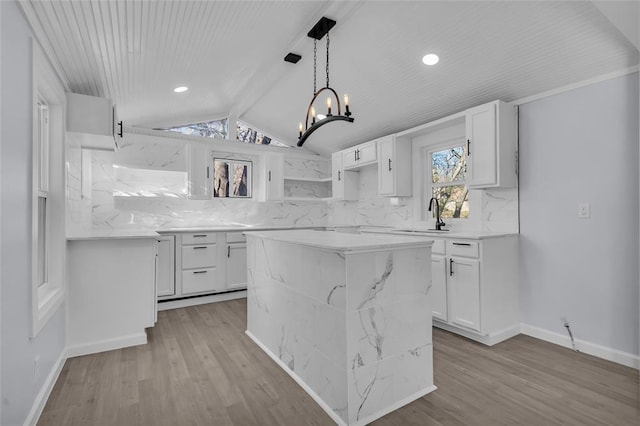 kitchen with backsplash, vaulted ceiling, sink, pendant lighting, and white cabinetry