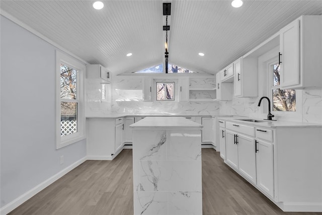 kitchen with backsplash, a center island, white cabinets, and sink