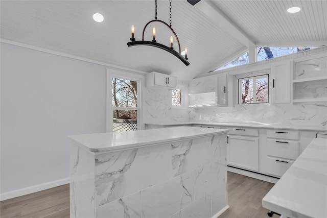 kitchen featuring light stone countertops, light wood-type flooring, white cabinets, a kitchen island, and hanging light fixtures