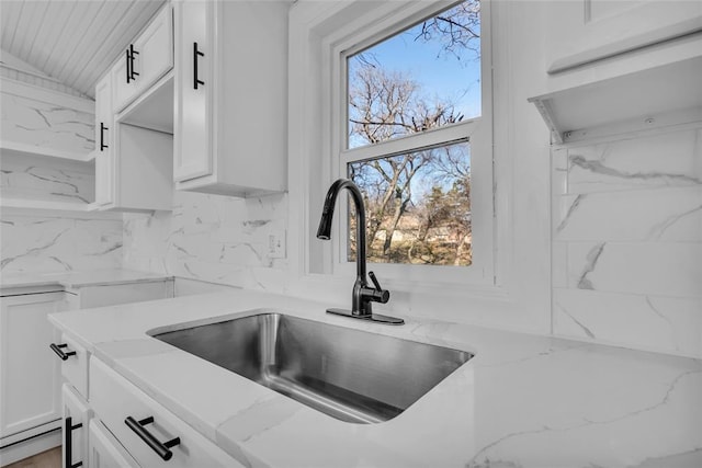 details with light stone countertops, decorative backsplash, white cabinets, and sink