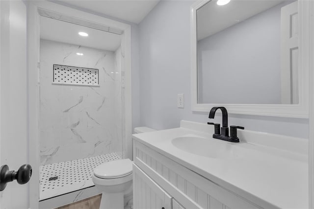 bathroom featuring tiled shower, vanity, hardwood / wood-style flooring, and toilet