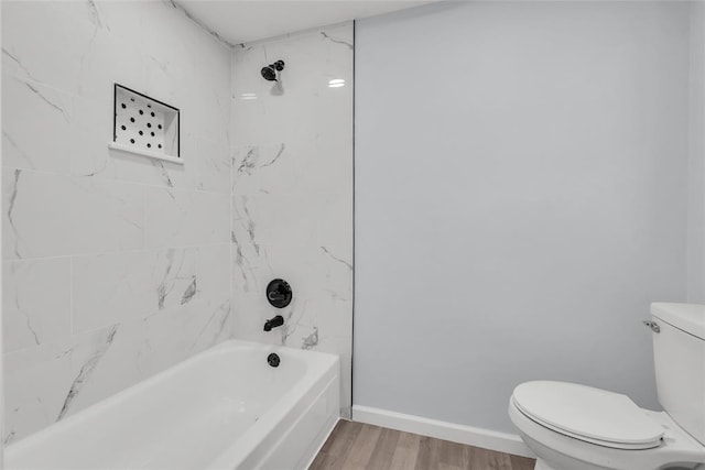 bathroom with hardwood / wood-style floors, toilet, and tiled shower / bath