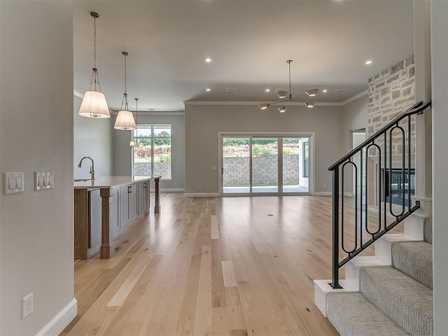 2408 Lazio Way, Edmond, OK 73034 - unfurnished living room with a chandelier, ornamental molding, light wood finished floors, recessed lighting, and stairs