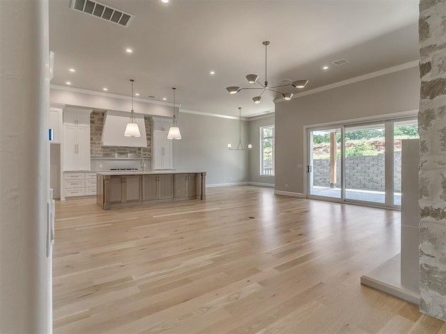2408 Lazio Way, Edmond, OK 73034 - unfurnished living room featuring crown molding, light wood-style floors, a chandelier, and recessed lighting