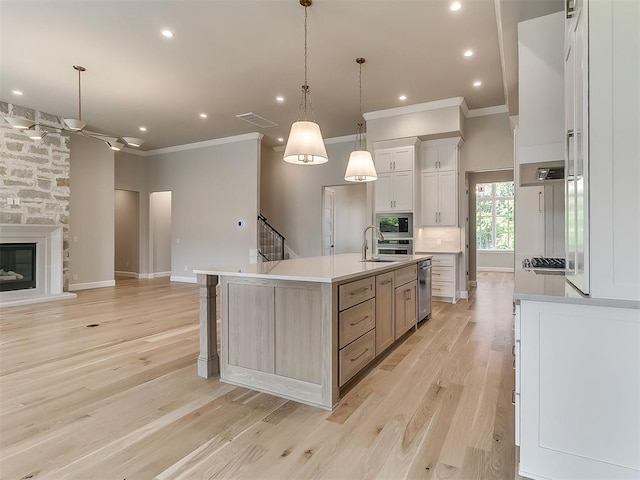 2408 Lazio Way, Edmond, OK 73034 - kitchen with appliances with stainless steel finishes, ornamental molding, light wood-style floors, an island with sink, and open floor plan