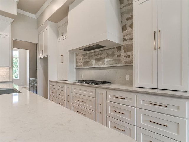 2408 Lazio Way, Edmond, OK 73034 - kitchen featuring premium range hood, decorative backsplash, white cabinets, crown molding, and stainless steel gas stovetop