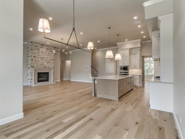 2408 Lazio Way, Edmond, OK 73034 - kitchen featuring appliances with stainless steel finishes, light countertops, open floor plan, an island with sink, and hanging light fixtures