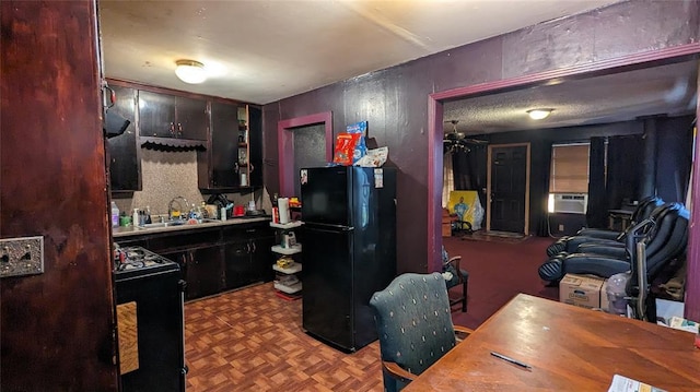 kitchen featuring gas range oven, a sink, and freestanding refrigerator