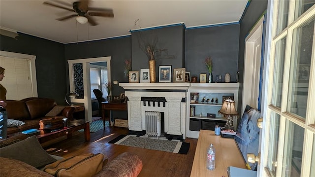 living room featuring ceiling fan, wood finished floors, and a fireplace with flush hearth