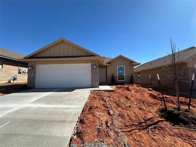 single story home featuring a garage, driveway, brick siding, and board and batten siding