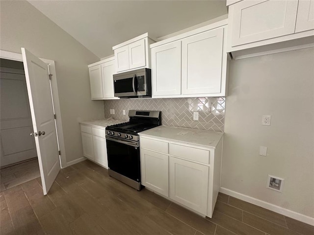 kitchen with lofted ceiling, tasteful backsplash, appliances with stainless steel finishes, and white cabinets