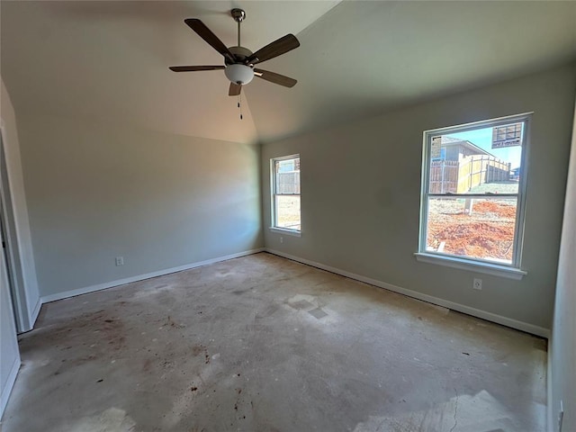 spare room featuring vaulted ceiling, unfinished concrete flooring, and baseboards