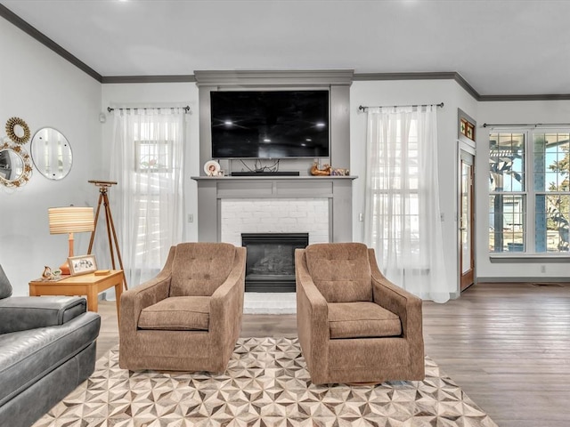 living room featuring light wood-type flooring, ornamental molding, a wealth of natural light, and a brick fireplace