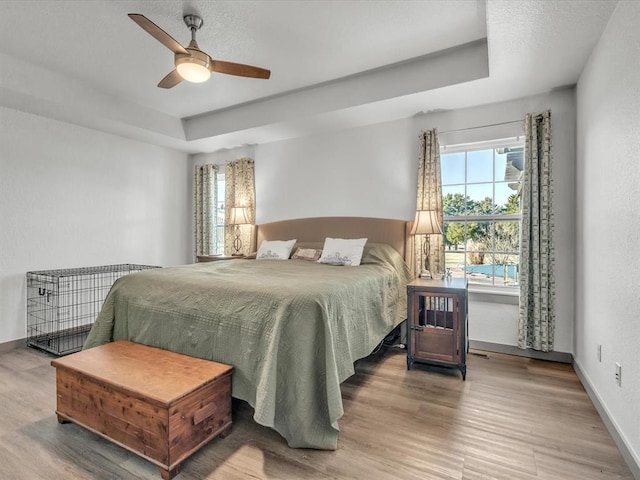 bedroom with a tray ceiling, multiple windows, and ceiling fan