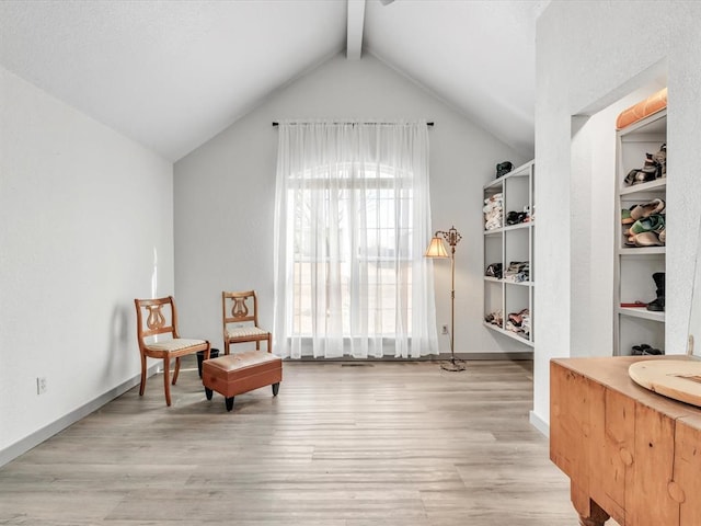 sitting room with lofted ceiling with beams and light wood-type flooring