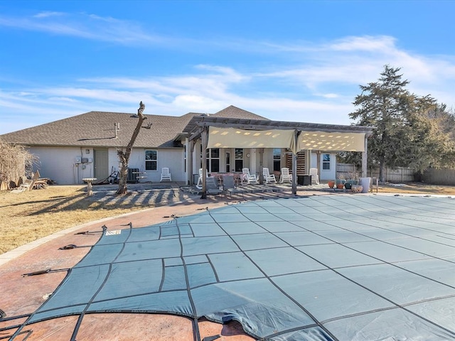 back of property with a patio area, a pergola, and a covered pool