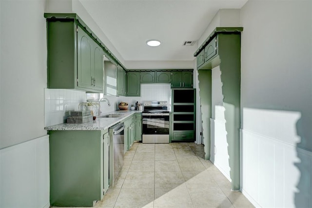 kitchen with appliances with stainless steel finishes, light stone counters, green cabinets, and sink