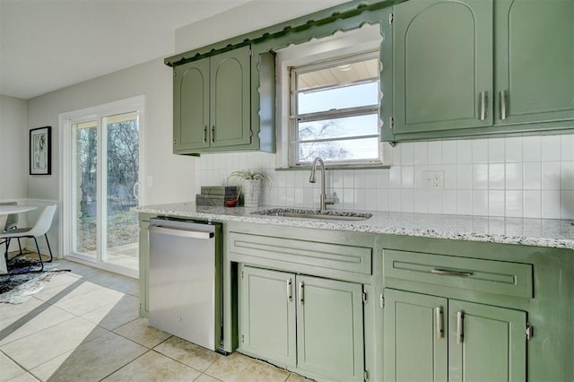 kitchen featuring dishwasher, green cabinets, sink, light tile patterned flooring, and light stone counters