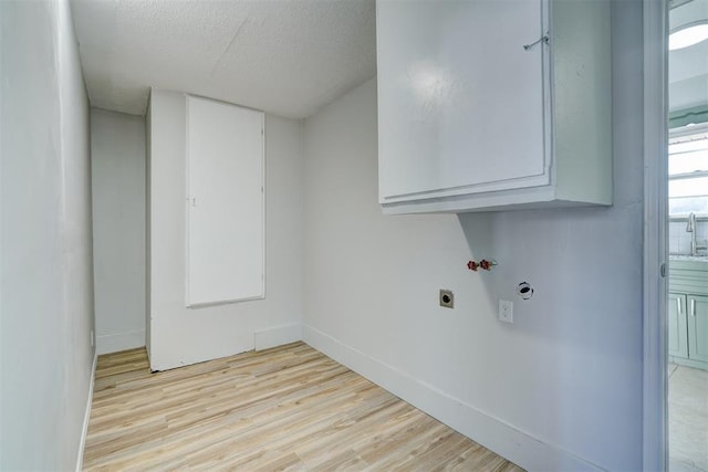 washroom with washer hookup, cabinets, hookup for an electric dryer, light hardwood / wood-style floors, and a textured ceiling