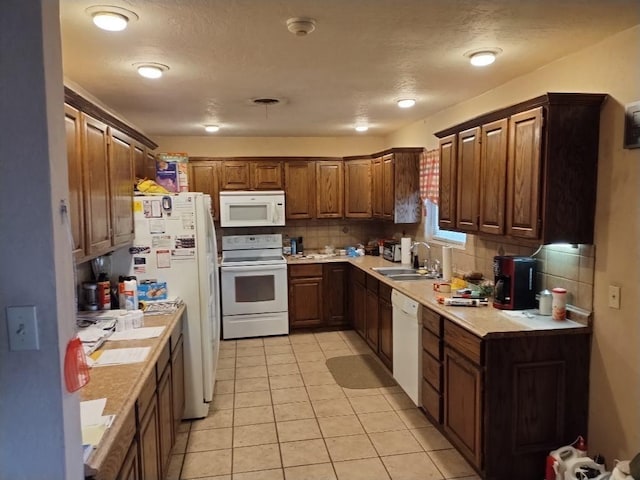 kitchen with light tile patterned floors, white appliances, backsplash, and sink