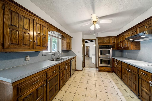 kitchen with exhaust hood, sink, a textured ceiling, appliances with stainless steel finishes, and light tile patterned flooring