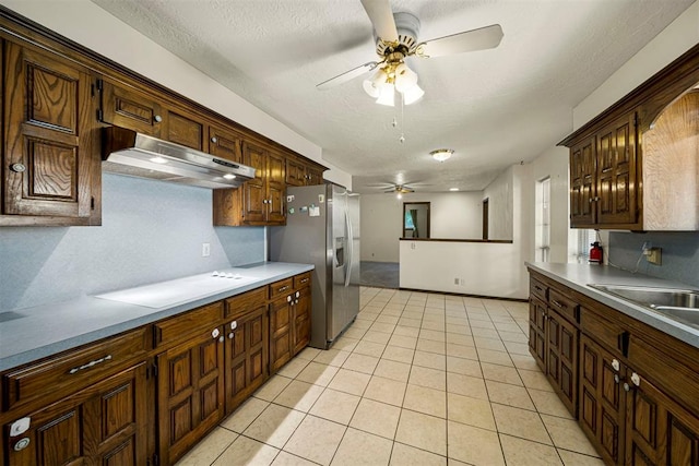 kitchen with sink, decorative backsplash, stainless steel fridge, light tile patterned floors, and stovetop