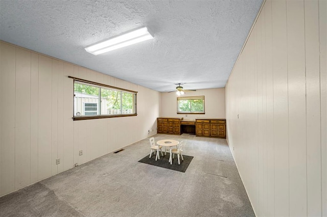 spare room featuring light carpet, built in desk, and wood walls