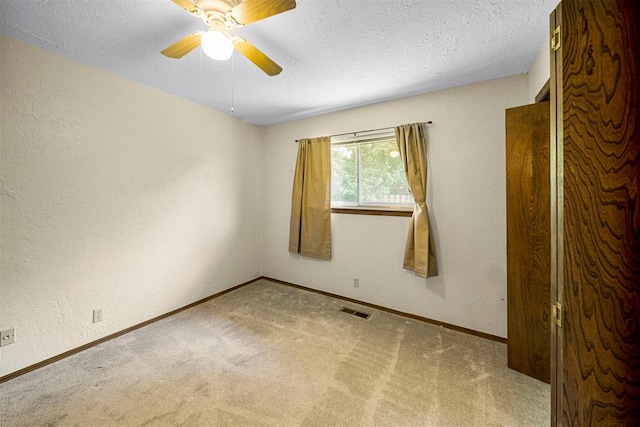 carpeted empty room with ceiling fan and a textured ceiling